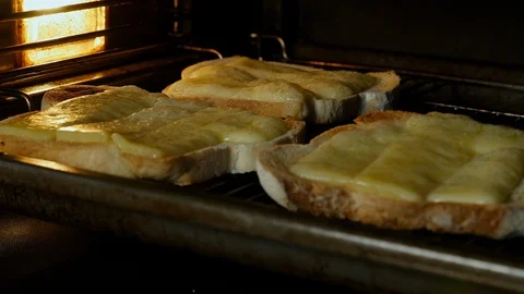 Cheese on toast bubbles under a grill Stock Footage 98660626