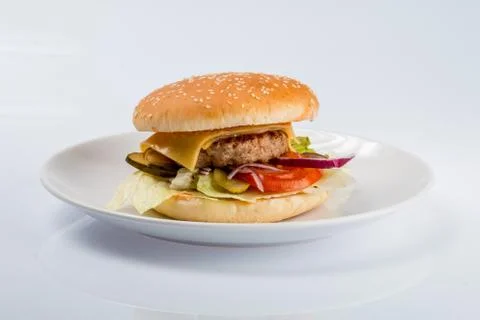 Cheeseburger with beef cutlet, bacon, tomatoes and cheese slices, seasoned wi Stock Photos