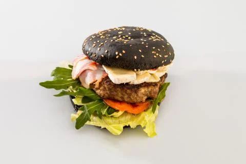 Cheeseburger with black bread, beef cutlet, bacon, tomatoes and cheese slices Foto stock