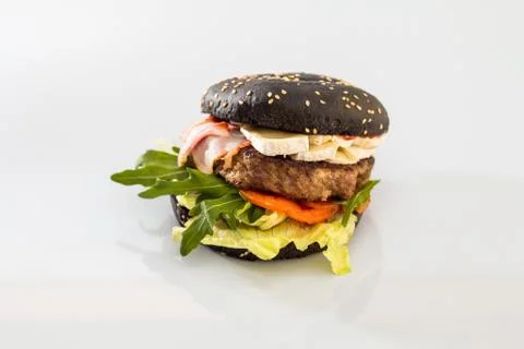 Cheeseburger with black bread, beef cutlet, bacon, tomatoes and cheese slices Stock Photos