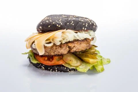 Cheeseburger with black bread, beef cutlet, bacon, tomatoes and cheese slices Stock Photos