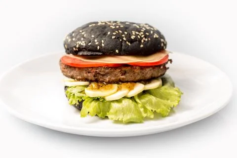 Cheeseburger with black bread, beef cutlet, bacon, tomatoes and cheese slices Stock Photos