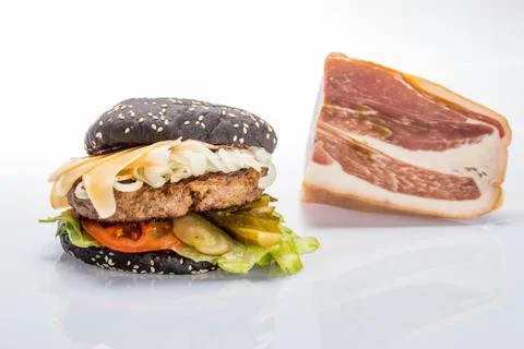 Cheeseburger with black bread, beef cutlet, bacon, tomatoes and cheese slices Foto stock