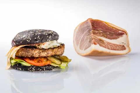 Cheeseburger with black bread, beef cutlet, bacon, tomatoes and cheese slices Foto stock
