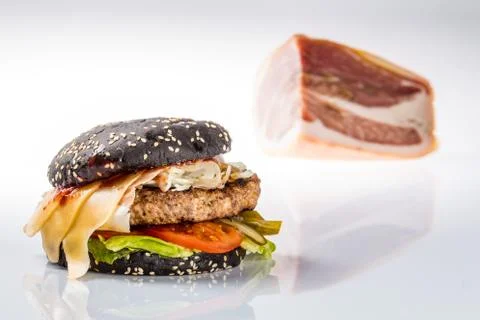 Cheeseburger with black bread, beef cutlet, bacon, tomatoes and cheese slices Foto stock