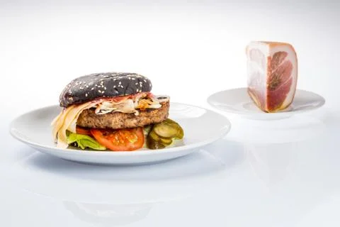 Cheeseburger with black bread, beef cutlet, bacon, tomatoes and cheese slices Stock Photos