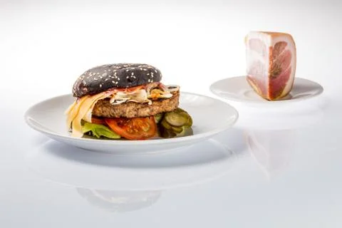 Cheeseburger with black bread, beef cutlet, bacon, tomatoes and cheese slices Stock Photos