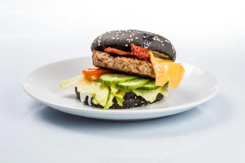 Cheeseburger with black bread, beef cutlet, bacon, tomatoes and cheese slices Stock Photos