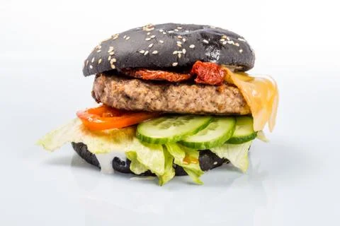 Cheeseburger with black bread, beef cutlet, bacon, tomatoes and cheese slices Foto stock