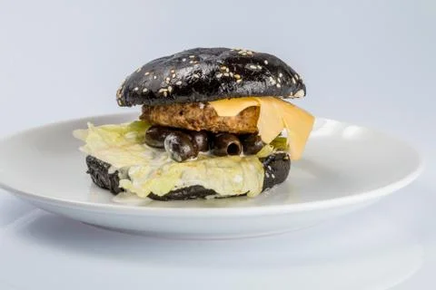 Cheeseburger with black bread, beef cutlet, bacon, tomatoes and cheese slices Foto stock