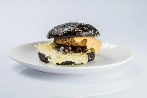 Cheeseburger with black bread, beef cutlet, bacon, tomatoes and cheese slices Stock Photos