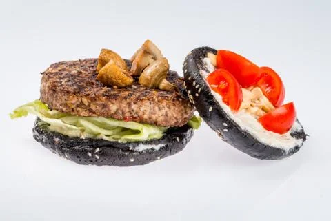 Cheeseburger with black bread, beef cutlet, bacon, tomatoes and cheese slices Stock Photos