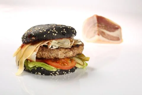 Cheeseburger with black bread, beef cutlet, bacon, tomatoes and cheese slices Stock Photos