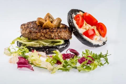 Cheeseburger with black bread, beef cutlet, bacon, tomatoes and cheese slices Stock Photos