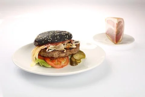 Cheeseburger with black bread, beef cutlet, bacon, tomatoes and cheese slices Stock Photos
