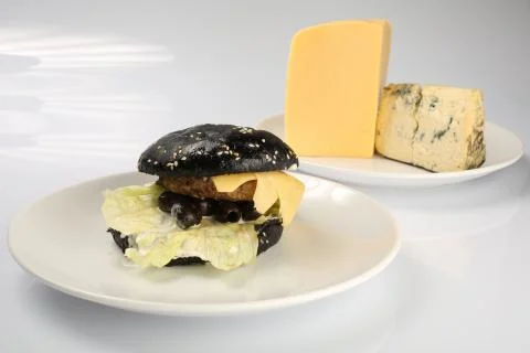 Cheeseburger with black bread, beef cutlet, bacon, tomatoes and cheese slices Stock Photos
