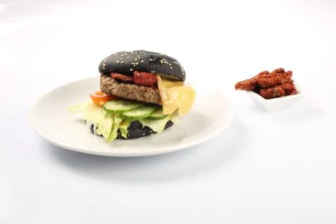 Cheeseburger with black bread, beef cutlet, bacon, tomatoes and cheese slices Foto stock