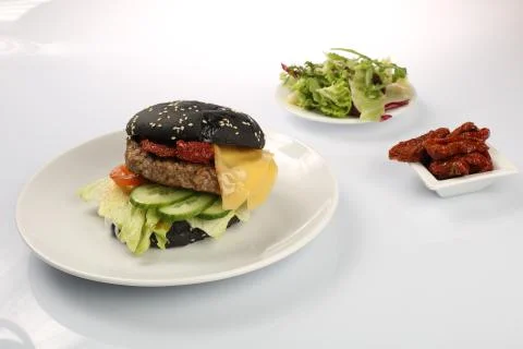 Cheeseburger with black bread, beef cutlet, bacon, tomatoes and cheese slices Stock Photos