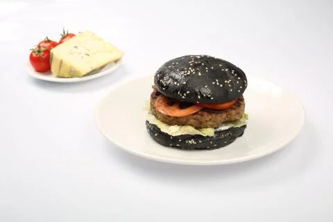 Cheeseburger with black bread, beef cutlet, bacon, tomatoes and cheese slices Stock Photos