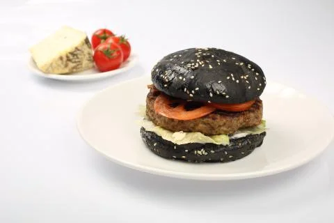 Cheeseburger with black bread, beef cutlet, bacon, tomatoes and cheese slices Stock Photos