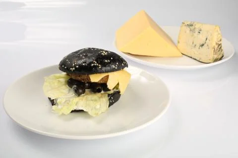 Cheeseburger with black bread, beef cutlet, bacon, tomatoes and cheese slices Stock Photos