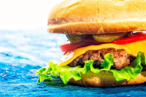Cheeseburger closeup on a blue background Stock Photos