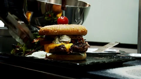 Cheeseburger preparation salad placement on dish moving camera Video stock 129097567