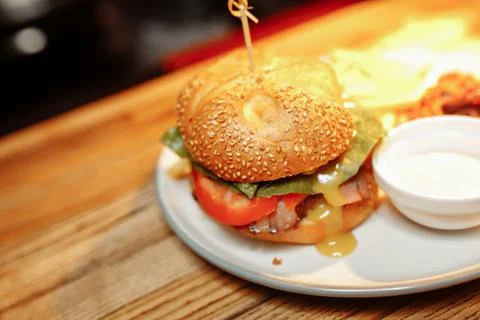 Cheeseburgers and fries on table top with onion, tomato, lettuce and cheese Stock-Fotos