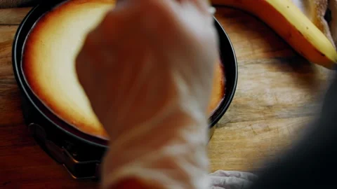 The cheesecake is gently separated from the baking mold using a knife Stock Footage 331638117