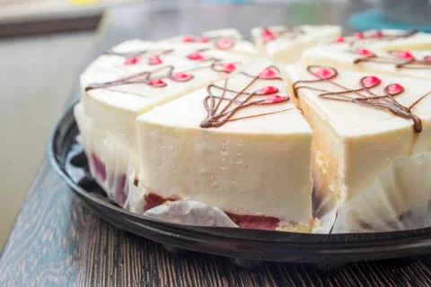 Cheesecake with raspberry jelly on black dish on a wooden table. Sliced chees Stock Photos