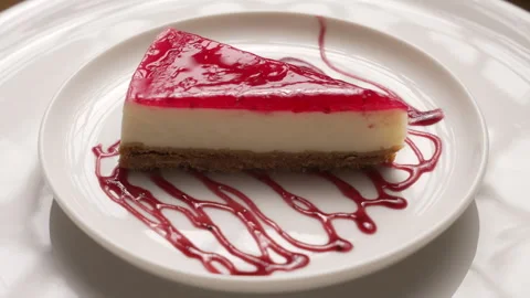 Cheesecake with a raspberry jelly topping, artistically drizzled with sauce Stock Footage 335393926