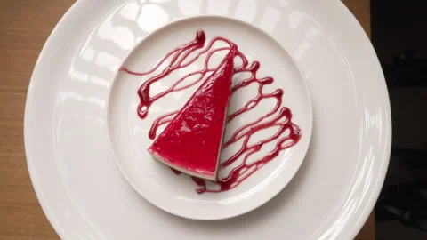 Cheesecake with a raspberry jelly topping, artistically drizzled with sauce 库存影片 335394562