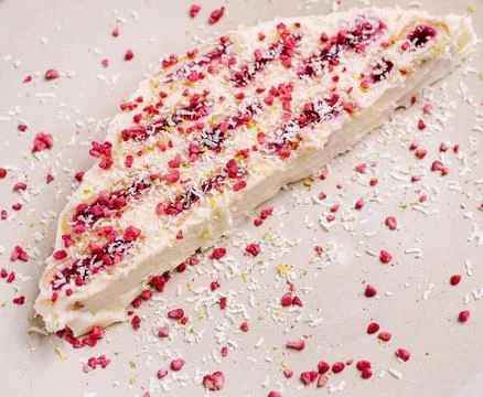 Cheesecake slice with raspberry and coconut sprinkles on plate Stock Photos