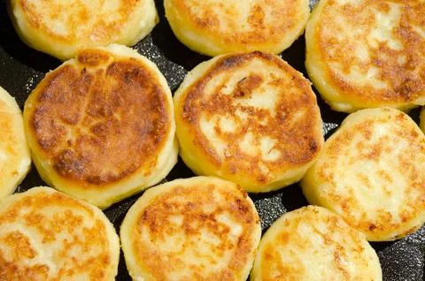 Cheesecakes are fried in a pan. The process of preparing delicious homemade.. Stock Photos