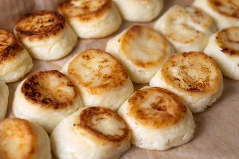 Cheesecakes on a baking sheet, cook in the dining room. Beautiful, rosy and Photos