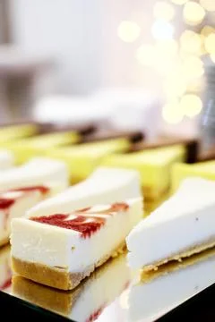 Cheesecakes on a mirror tray stand on a buffet table against the background.. Stock Photos