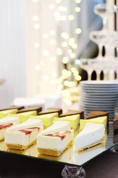 Cheesecakes on a mirror tray stand on a buffet table against the background.. Stock Photos
