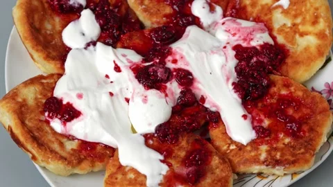 Cheesecakes with raspberry jam and sour cream on a plate rotates on a turntable Stock Footage 159445319