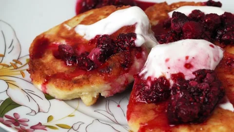 Cheesecakes with raspberry jam and sour cream on a plate rotates on a turntable Stock Footage 159445489