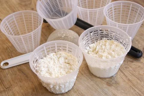 Cheesemaker preparing fresh ricotta cheese using plastic draining baskets a.. Foto stock