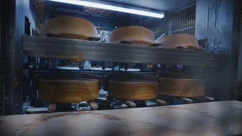 Cheesemaking machinery processing cheese wheels in a modern dairy factory Stock Photos