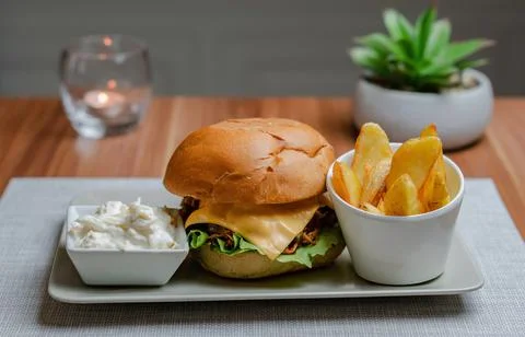 Cheesy Pulled Pork Burger with Chips and Cabbage salad, Hotel background Stock Photos