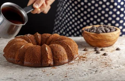 A chef is about to pour melted chocolate on top of a round cake Stock Photos