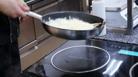 Chef actively working in the kitchen of restaurant mixed onion are roasted in a Stock Footage 107193075