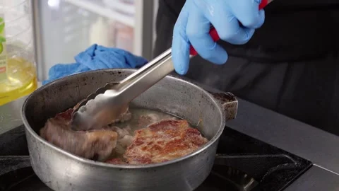 Chef adding and turning steaks in frying pan Stock Footage 286309955