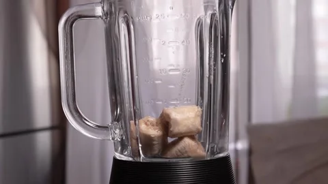 Chef adding banana slices into blender glass container 库存影片 297456735