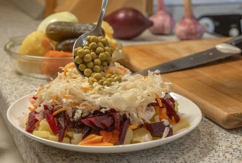 Chef adding canned green peas to vinaigrette salad made from sauerkraut, on.. Stock Photos