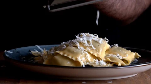Chef adding cheese  to ravioli on a black background Stock Footage 128504550