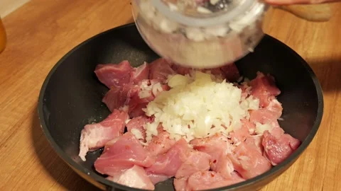 Chef adding chopped onions to raw pork meat Stock-Footage 342758525