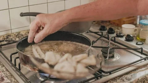Chef adding codfish dough balls to bubbling frying oil 库存影片 295189775